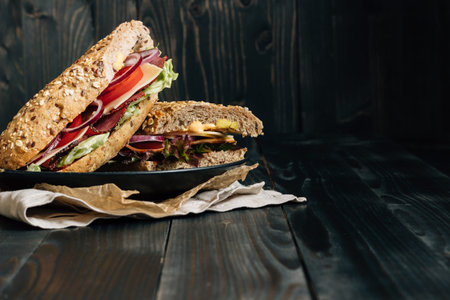 Fresh delicious submarine sandwich on the wooden dark table, with copy space.