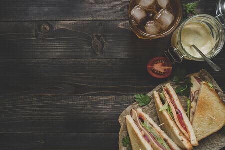 Fresh delicious club sandwich, sauces and drink on the wooden dark table with copy space, top viewの写真素材