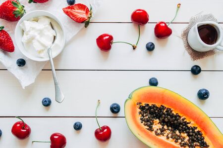 Summer fruits. Fresh juicy berries and papaya on the white wooden table, top view.の写真素材