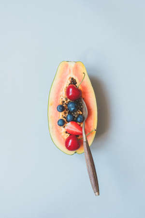 Summer fruits. Fresh juicy berries and papaya on the blue background, top view.の写真素材