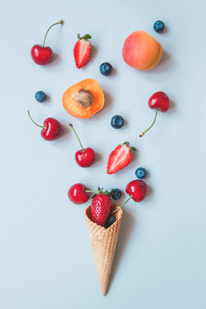 Fresh juicy berries and sweet waffle cone on the blue background, top view.の写真素材