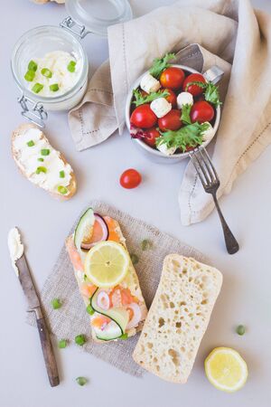 Fresh tomato salad and ciabatta bread with cream cheese and salmon on the gray background.の写真素材