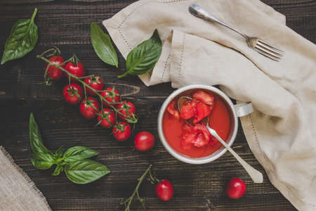 Fresh cherry tomatoes, basil and tomato sauce on the wooden table, top view.の写真素材