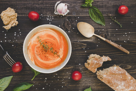 Tomato cream soup with bread on the wooden table, top view.の写真素材