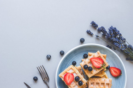 Homemade belgian waffles with blueberries and strawberries on the light blue table with copy space.の写真素材