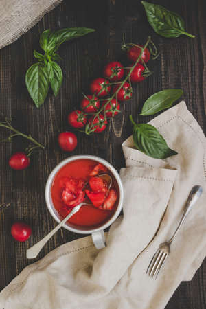 Fresh cherry tomatoes, basil and tomato sauce on the wooden table, top view.の写真素材