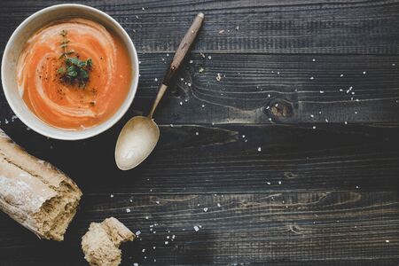 Tomato cream soup with bread on the wooden table, top view. With copy space.の写真素材