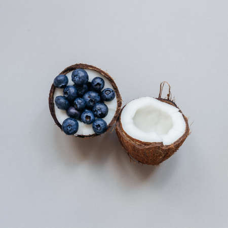Ripe coconut with blueberry on the gray background, top view.の写真素材