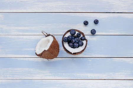 Ripe coconut with blueberry on the blue wooden background, top view.の写真素材