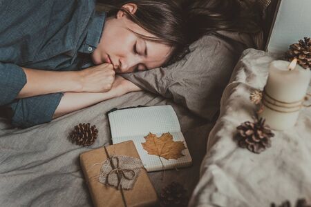 Cozy home. Autumn mood. Woman sleeping in bed by the window. Selective focus.の写真素材