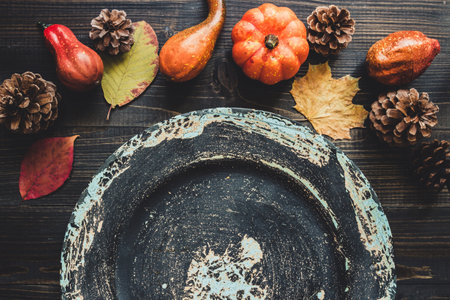 Autumn background with copy space. Empty plate and autumn decoration on the wooden table.の写真素材