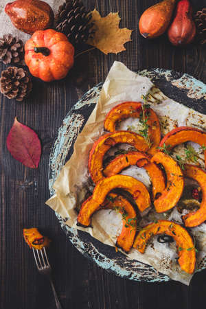 Baked pumpkin and autumn decoration on the wooden table, top view.の写真素材