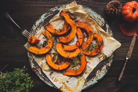 Delicious baked pumpkin with thyme and chilli on the wooden table, top view.の写真素材
