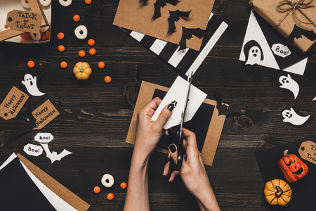 Halloween preparation. Hands making halloween cards and decoration using craft paper.の写真素材