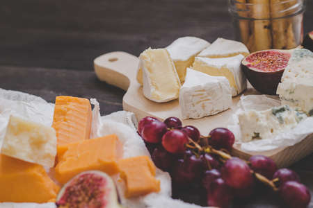 Various types of cheese with fruits and nuts on the wooden dark table. Selective focus.の写真素材