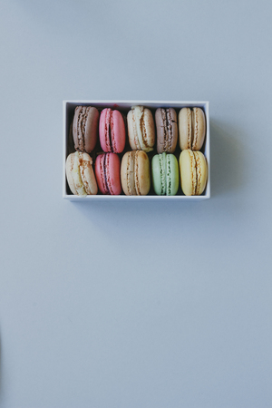 Cute gift box with delicious colorful macaroons on the light blue background, top view.の写真素材