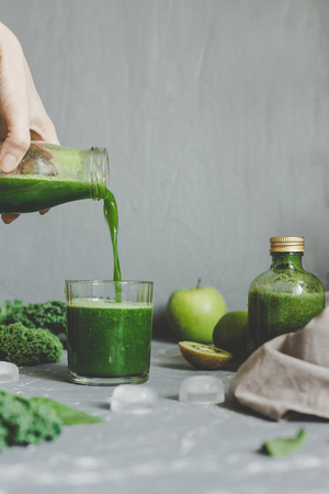 Hands pouring healthy green smoothie in a jar. Clean eating conceptの写真素材
