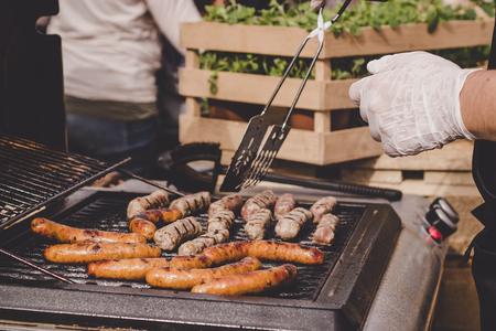 Cooking delicious juicy meat sausages on the grill outdoor.の写真素材