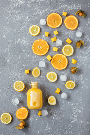 Sweet yellow smoothie with yellow fruits on gray wooden table, top view.の写真素材