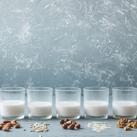 Different kinds of vegan non-dairy milk in glasses on wooden background with copy space.の写真素材