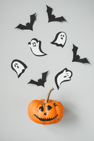 Happy halloween. Funny halloween pumpkin with paper bats and ghosts on gray background.の写真素材