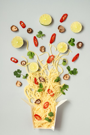 Asian food. Asian egg noodles with different ingredients in paper box, top view.の写真素材