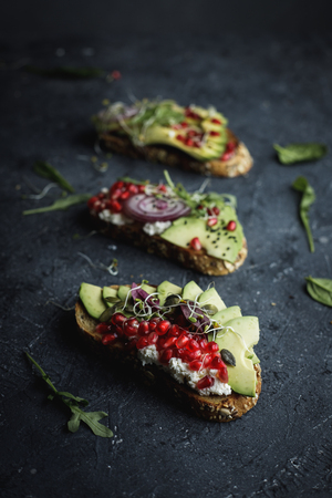 Avocado toasts with seeds and sprouts on black table, close upの写真素材