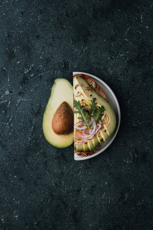 Healthy food concept. Half avocado and avocado toasts with avocado slices, pomegranate seeds and...