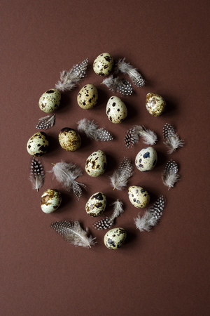 Easter egg made of quail eggs and feathers on brown background. Easter holiday concept.の写真素材