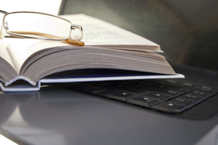 laptop with a book and reading glassesの写真素材
