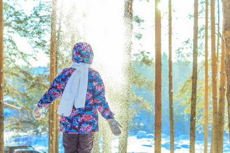 Girl throws snow in sunny winter forestの写真素材