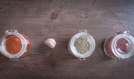 Garlic and spices in glass jars on wooden backgroundの写真素材