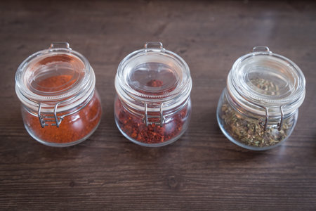 Garlic and spices in glass jars on wooden backgroundの写真素材