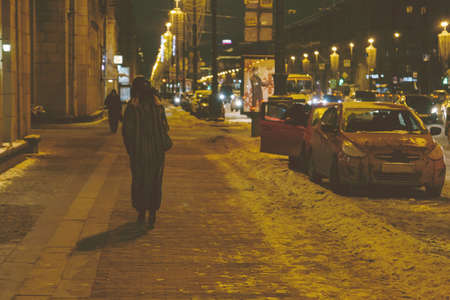 a woman walks down the street at night in the winterの写真素材