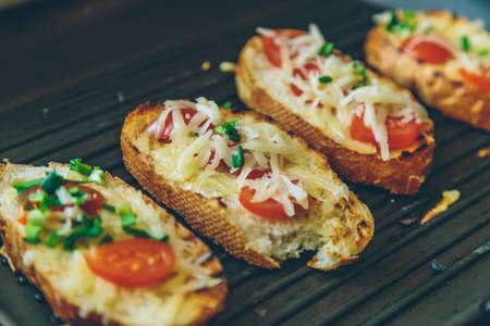 bread grilled with cheese, onions and tomatoes close upの写真素材