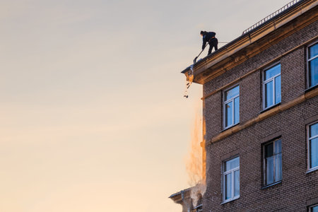 Worker throws snow from the roof