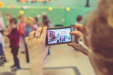woman taking a picture of children on the phone in kindergarten close upの写真素材