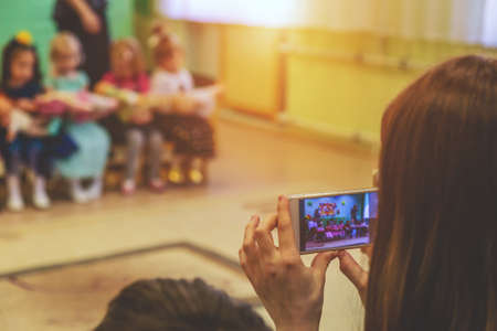 woman taking a picture of children on the phone in kindergarten close upの写真素材