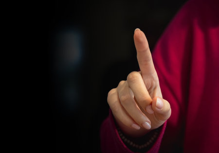 Woman hand pointing at something on black background with copy space, close upの写真素材