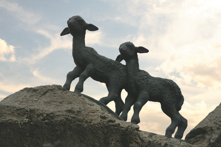 Sculpture of two lambs on the rocks on the evening backgroundの写真素材