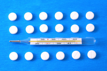 Pills and thermometer on a blue background