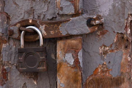 Texture of old gray painted wooden door with peeled paint and close-up of old rusty padlockの写真素材