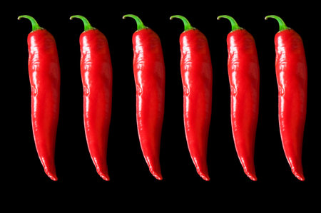 Six pods of hot red pepper and close up on black isolated background
