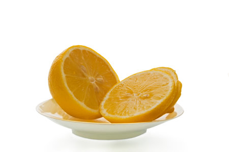Yellow ripe lemon sliced into wedges on a white plate on a white isolated background close up