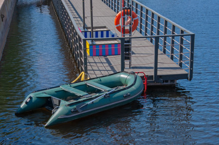 Inflatable boat and red life buoy on a wooden boat pier by the seaの写真素材