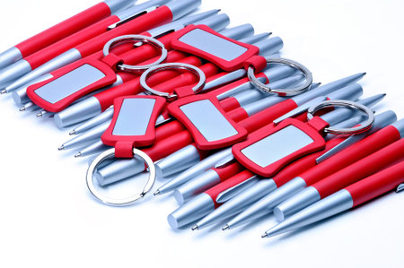 Silver-red metal pens and keychains isolated on white background.