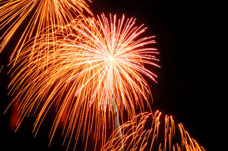 Flashes of red yellow and orange festive salute against the black skyの写真素材