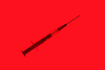 Plastic disposable syringe with a needle on red backgroundの写真素材