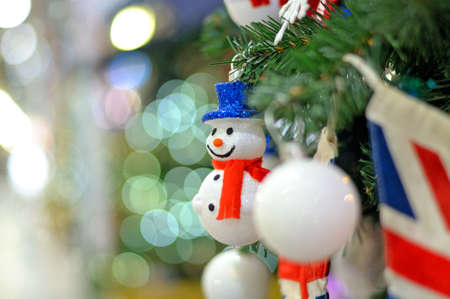 Christmas ornament a snowman on a Christmas fir-tree against from color firesの写真素材