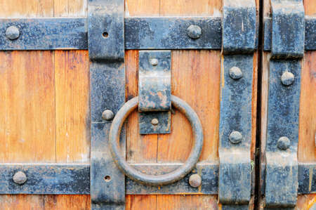 Part of the old wooden gates with handle in the form of ring studded with metal platesの写真素材